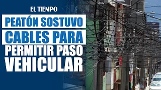 Pedestrian holds up cables to allow vehicles to pass | EL TIEMPO