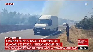 Truck full of hay bales, engulfed in flames on the road